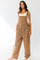 woman wearing a brown overall jumpsuit with side pockets and adjustable straps, styled casually without shoes