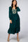 woman wearing a forest green long sleeve midi dress with floral embroidery and a waist tie