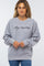 woman wearing a grey boy mama sweatshirt with black cursive text and blue jeans