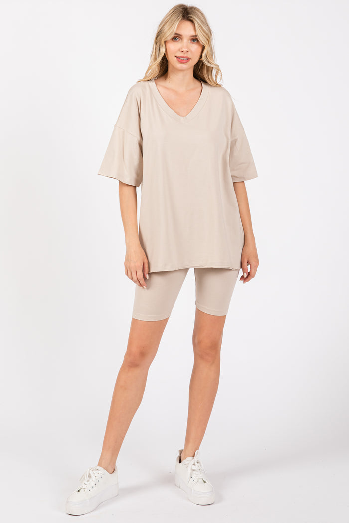 woman wearing a beige oversized v-neck t-shirt and matching bike shorts with white sneakers