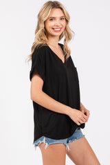 woman wearing a black short sleeve v-neck top with a front pocket and denim shorts