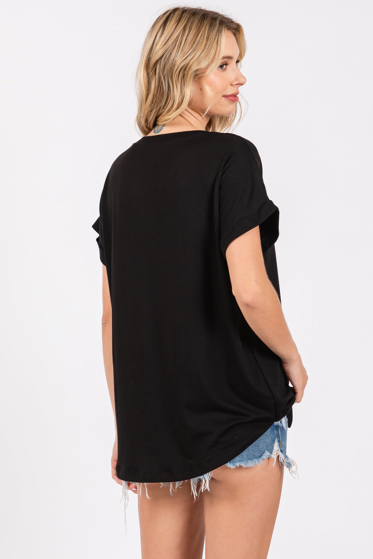 woman wearing a black oversized t-shirt with rolled sleeves and styled with distressed denim shorts