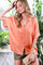 woman wearing an oversized peach button-up shirt with rolled sleeves and holding a clutch purse, styled with shorts