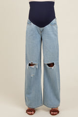 maternity wear high-waisted light blue distressed jeans with a navy belly band, model standing barefoot