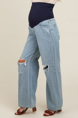 woman wearing light blue distressed maternity jeans with a navy belly band and side view of a visible baby bump