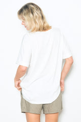 woman wearing a white oversized t-shirt and beige shorts, viewed from the back