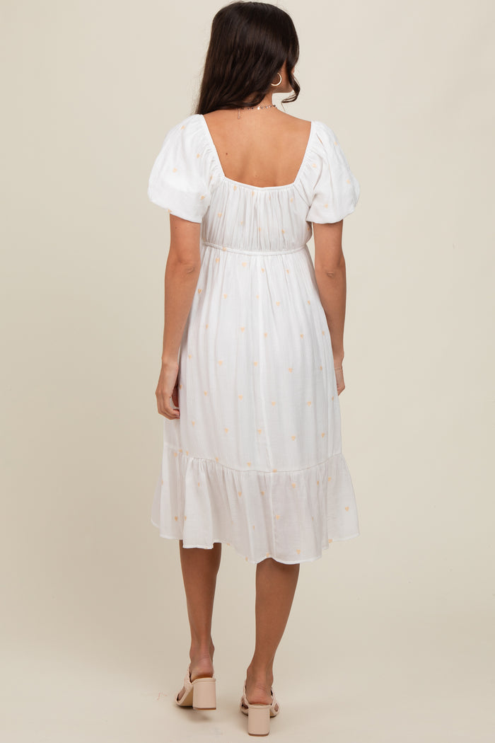woman wearing a white midi dress with puff sleeves and a ruffled hem, shown from the back