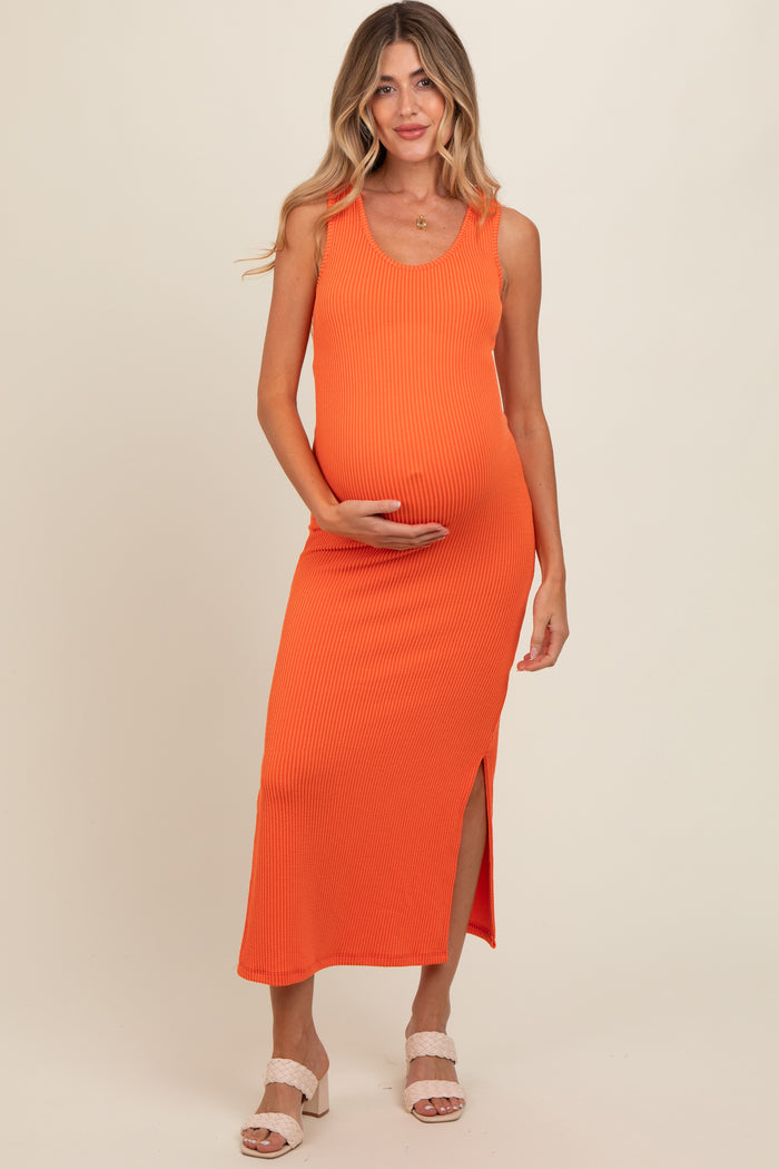 woman wearing a bright orange ribbed maternity dress with a side slit and holding her baby bump