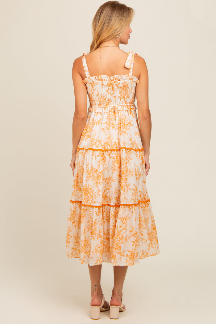 woman wearing a back view of a white midi dress with orange floral print and ruffled straps