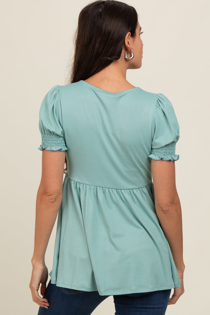 woman wearing a teal smocked back top with puff sleeves and a flared hem