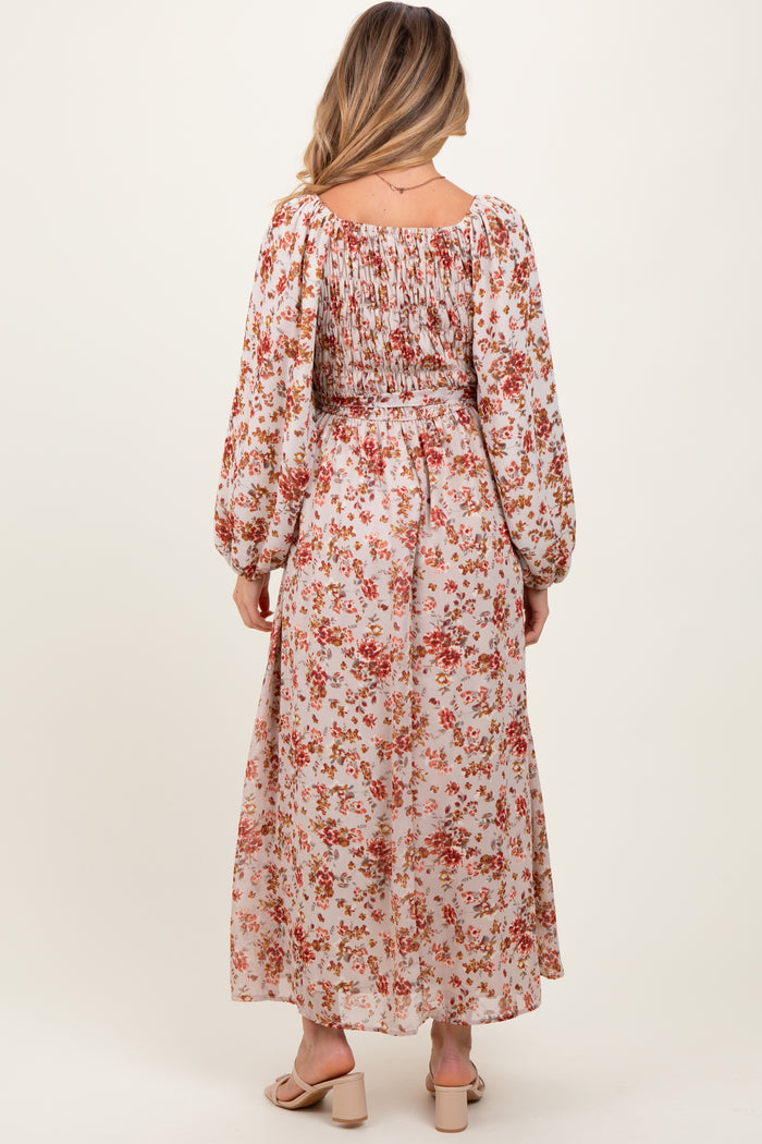 woman wearing a floral print maxi maternity dress with long sleeves and smocked detailing on the back