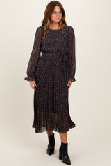 woman wearing a navy floral print midi dress with long sleeves and a tie waist, paired with black ankle boots