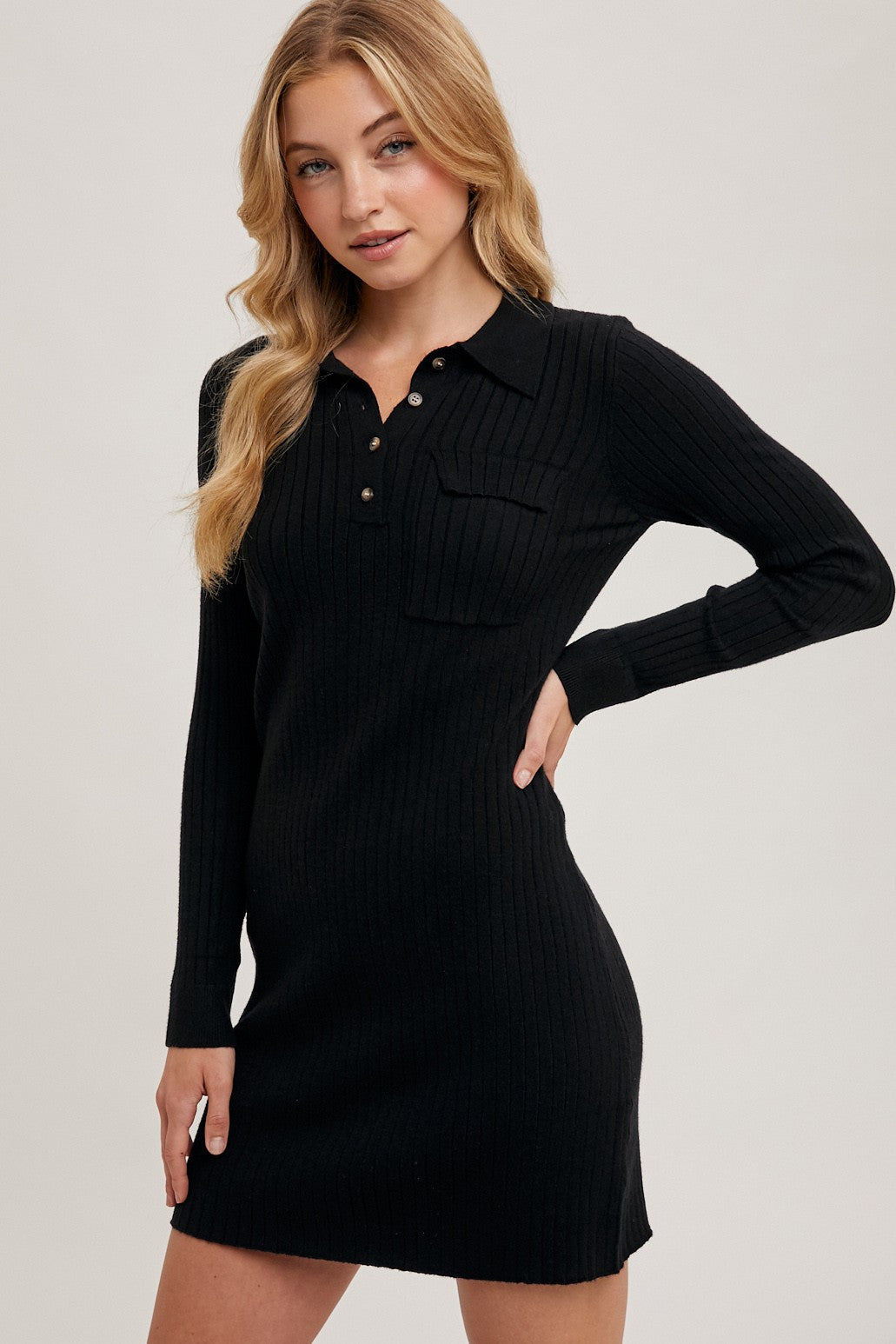 woman wearing a black ribbed long sleeve polo dress with button details and a chest pocket