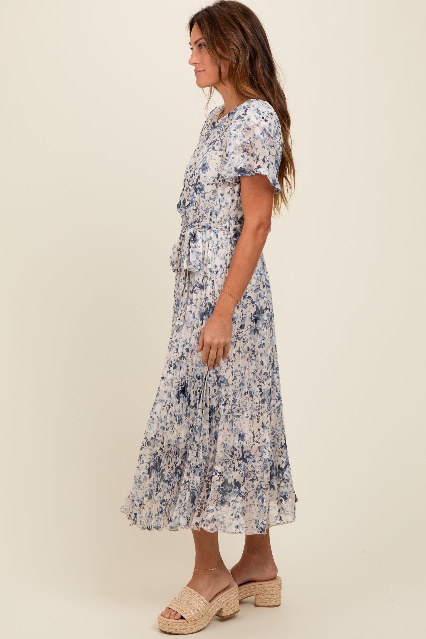 woman wearing a blue and white floral midi dress with short sleeves and a waist tie