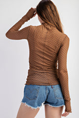 woman wearing a brown polka dot mesh long sleeve top paired with denim shorts, showing the back view