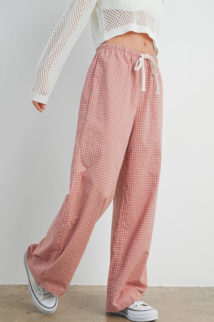 woman wearing pink checkered wide-leg pants with an elastic waistband and drawstring, paired with a white cropped top