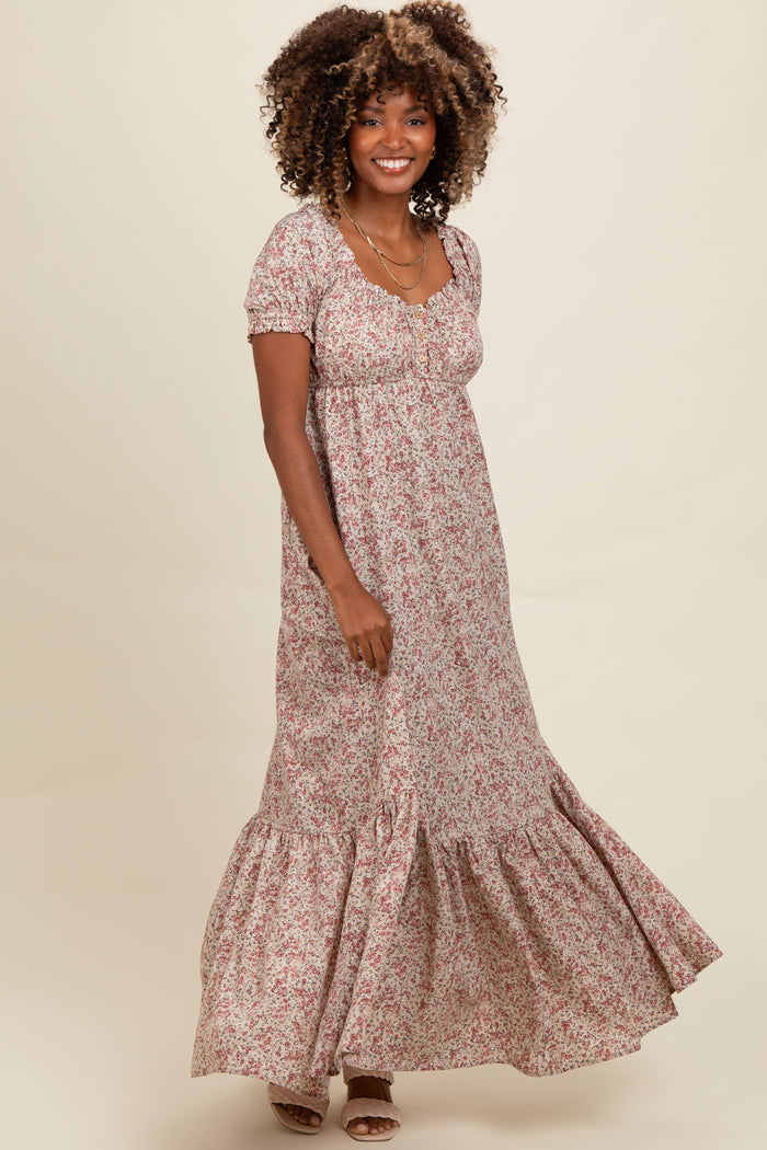 woman wearing a floral maxi dress with short puff sleeves and a tiered hem, smiling and standing against a neutral background