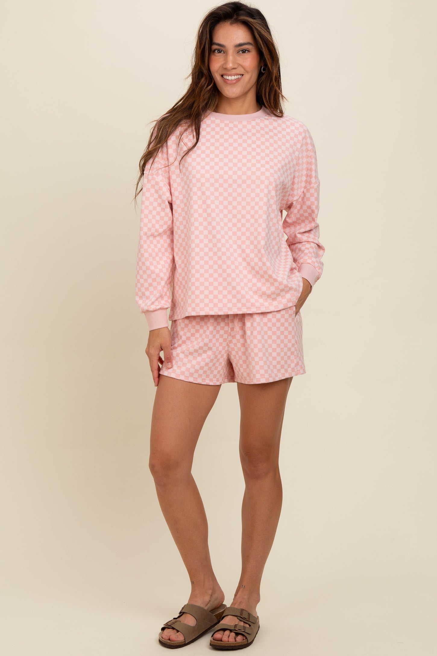 woman wearing a light pink checkerboard print long sleeve top and matching shorts with pockets
