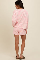 woman wearing a pink checkered loungewear set featuring a long sleeve top and shorts, viewed from the back