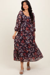 woman wearing a burgundy floral maxi dress with long sleeves and a tiered skirt