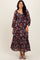 woman wearing a dark floral maxi dress with long sleeves and a ruffled hem, smiling at the camera