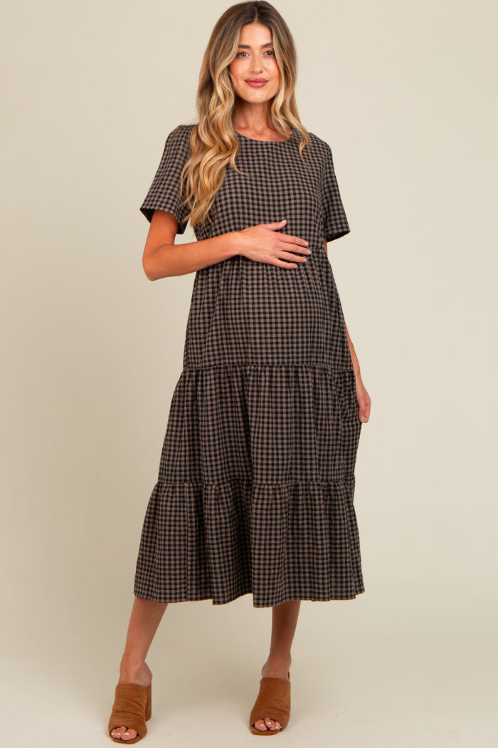 woman wearing a brown checkered maternity dress with short sleeves and a tiered skirt, holding her baby bump