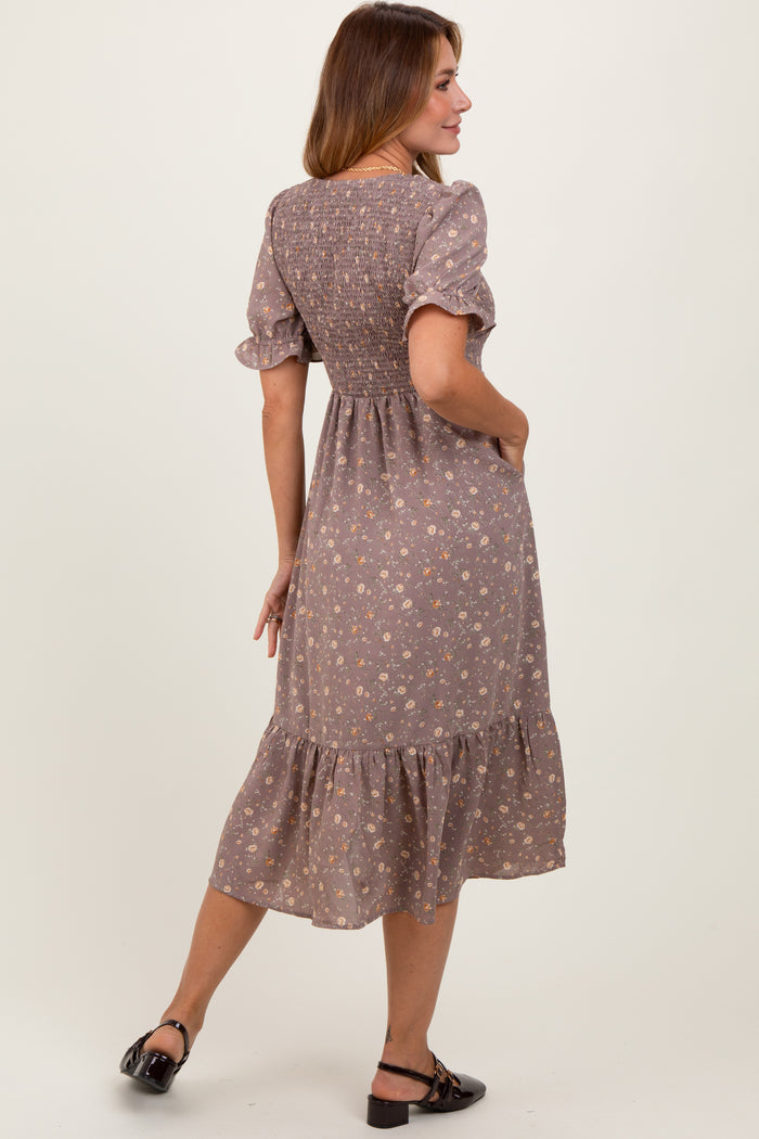 woman wearing a dusty mauve floral short sleeve dress with a smocked back and tiered hem, standing with her back to the camera