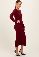 woman wearing a burgundy ribbed long sleeve midi dress with a fitted silhouette and side slit
