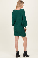 woman wearing a green cable knit sweater dress with balloon sleeves and ankle boots, shown from the back