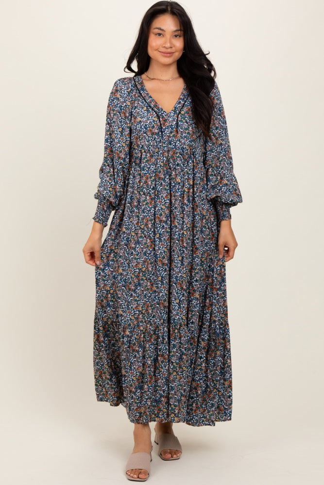woman wearing a navy blue floral maxi dress with long sleeves and a v-neckline, standing against a neutral background