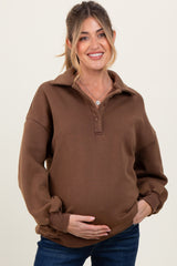 woman wearing a brown maternity pullover with a collar and relaxed fit, holding her baby bump