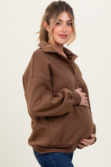 woman wearing a brown maternity pullover with a collar and holding her baby bump