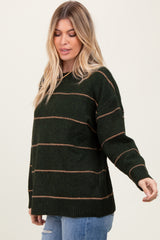 woman wearing a dark green striped sweater with earthy tone lines and relaxed fit, paired with blue jeans