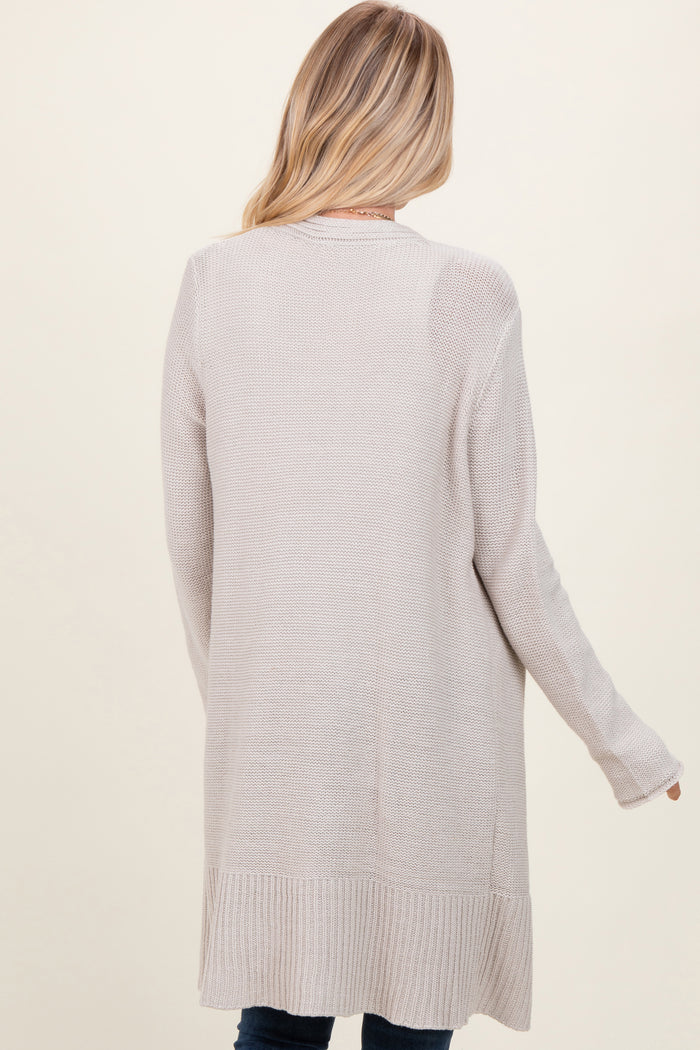 woman wearing a long beige cardigan styled with a relaxed fit, shown from the back