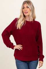 woman wearing a burgundy knit sweater with long sleeves and a relaxed fit, paired with blue jeans