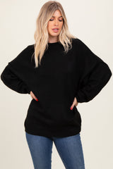 woman wearing an oversized black sweater with dropped shoulders and relaxed fit, paired with blue jeans
