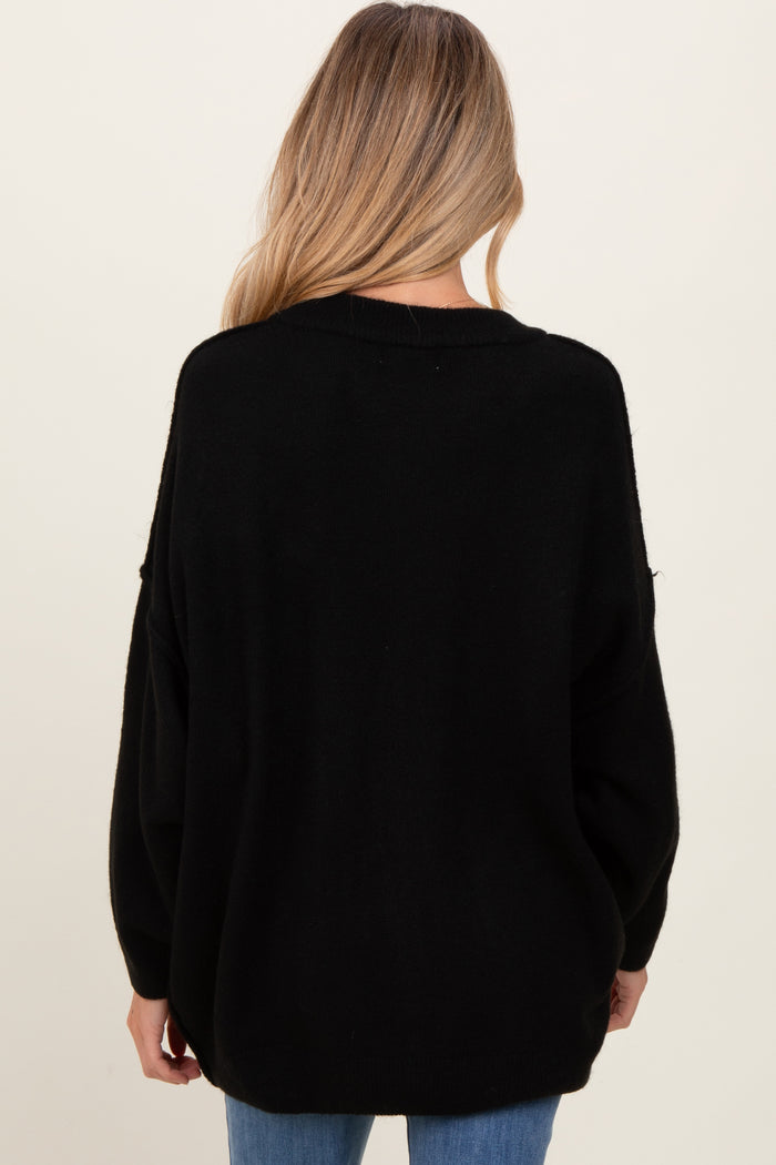 woman wearing a black oversized maternity sweater, viewed from the back with relaxed fit sleeves