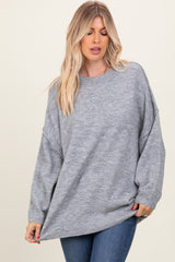 woman wearing a gray oversized sweater with dropped shoulders and a relaxed fit, paired with blue jeans
