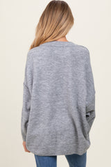 woman wearing a gray oversized maternity sweater, seen from the back, paired with blue jeans