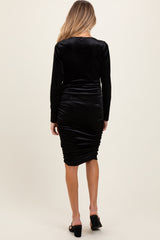 woman wearing a black velvet long sleeve maternity dress with ruching detail, showing her baby bump from behind