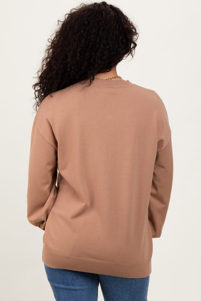 woman wearing a tan oversized sweater with long sleeves and a relaxed fit, shown from the back