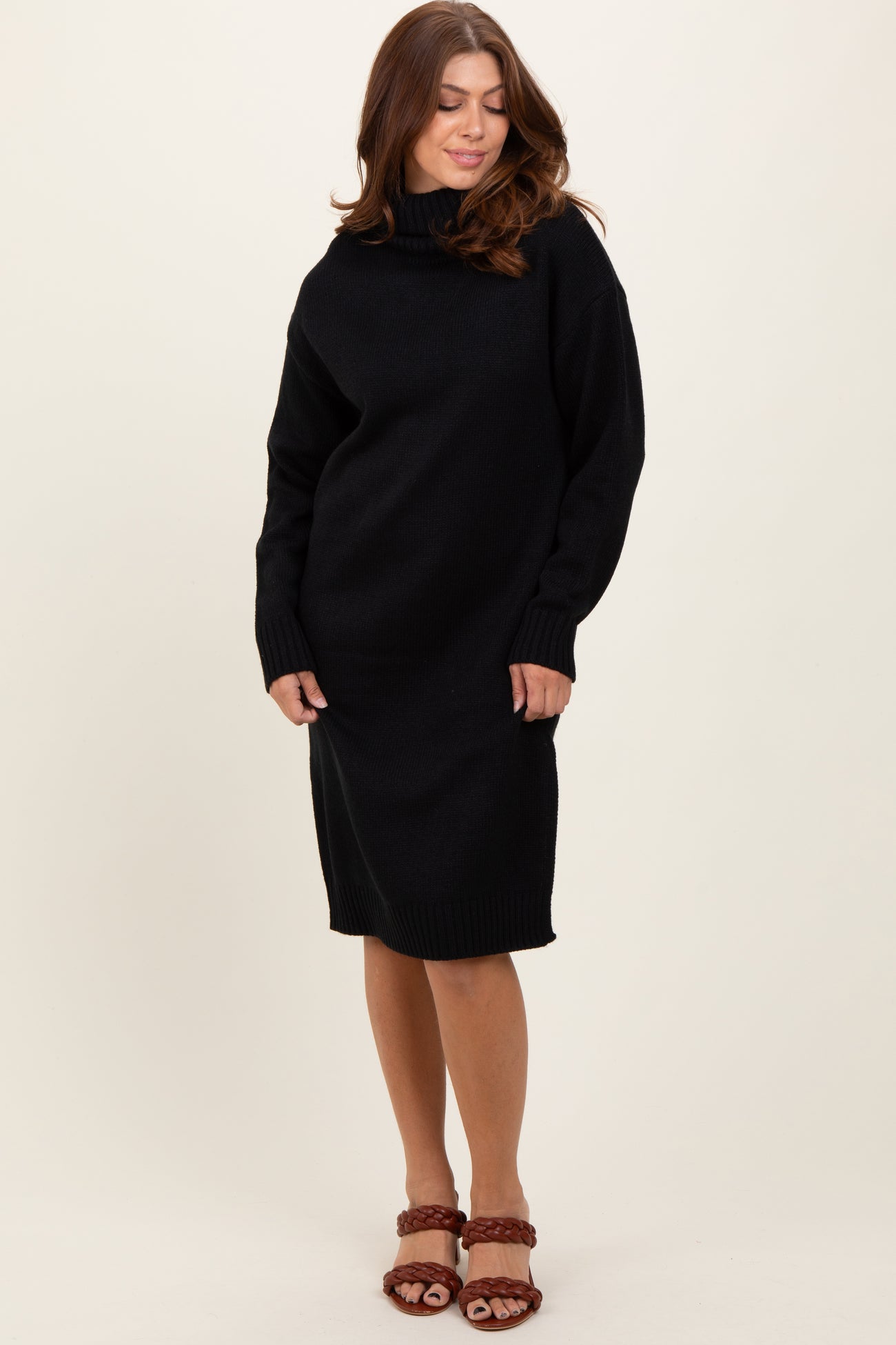 woman wearing a black oversized sweater dress with a high neckline and long sleeves