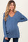 woman wearing a blue long sleeve maternity sweater with a v-neck and visible baby bump