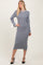 woman wearing a gray ribbed knitted midi dress with white cuffs and black high heels