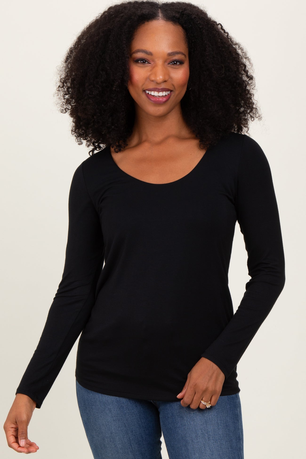 woman wearing a black long sleeve top with a scoop neckline and smiling at the camera
