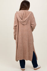 woman wearing a long beige maternity cardigan with a hood, seen from the back, casual style