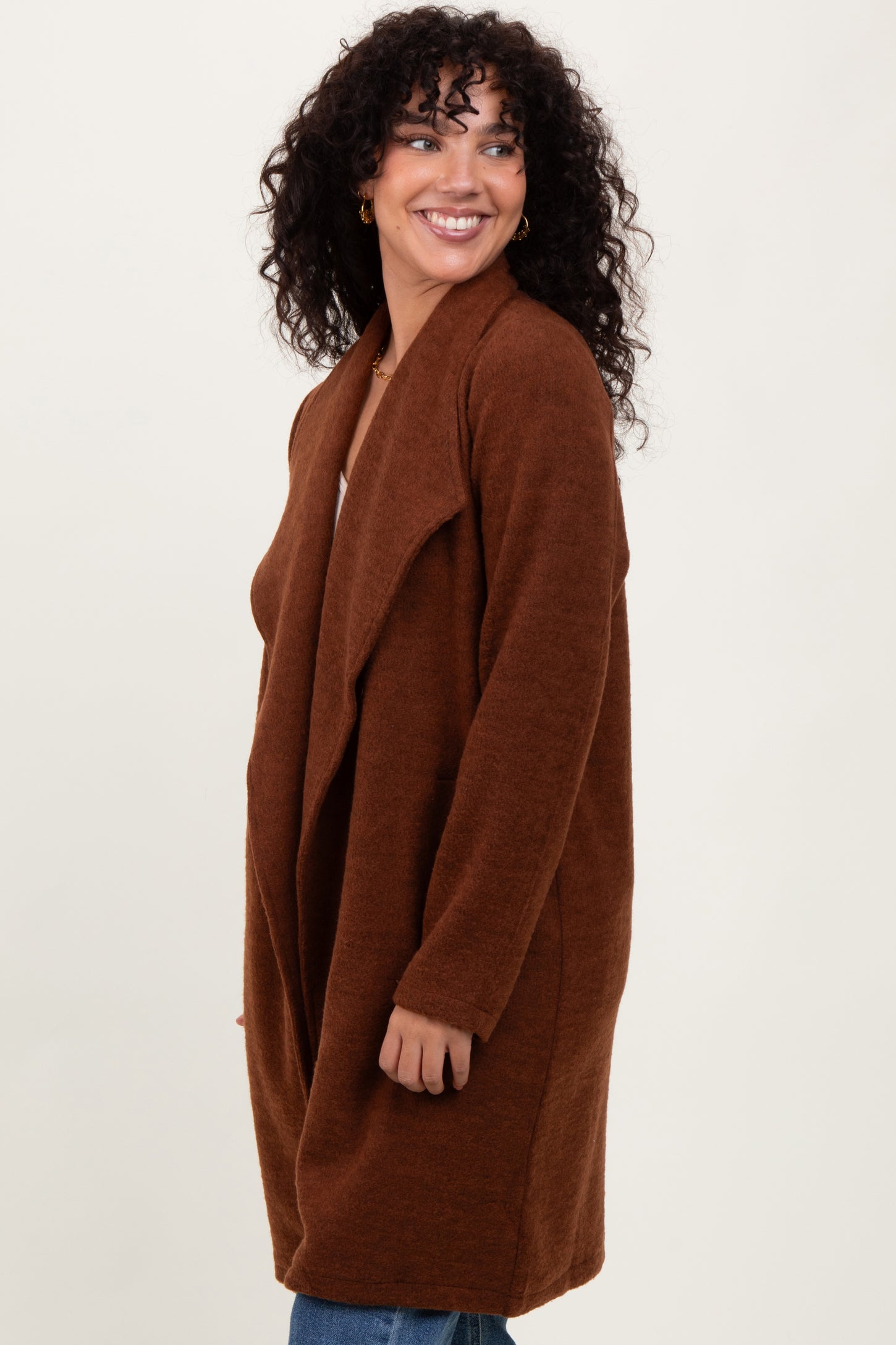 woman wearing a rust-colored long cardigan with an open front and a relaxed fit
