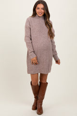 woman wearing a taupe maternity sweater dress with a mock neck and showing her baby bump, paired with brown knee-high boots