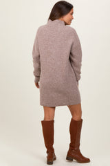 woman wearing a taupe knit maternity sweater dress with a high collar and long sleeves, paired with brown knee-high boots