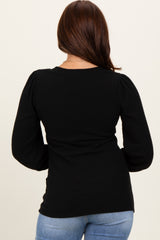 woman wearing a black ribbed long sleeve top with puff sleeves, viewed from the back